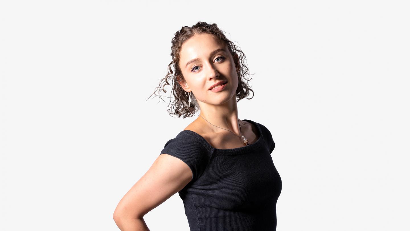 Headshot of female dancer in a black top with short curly hair