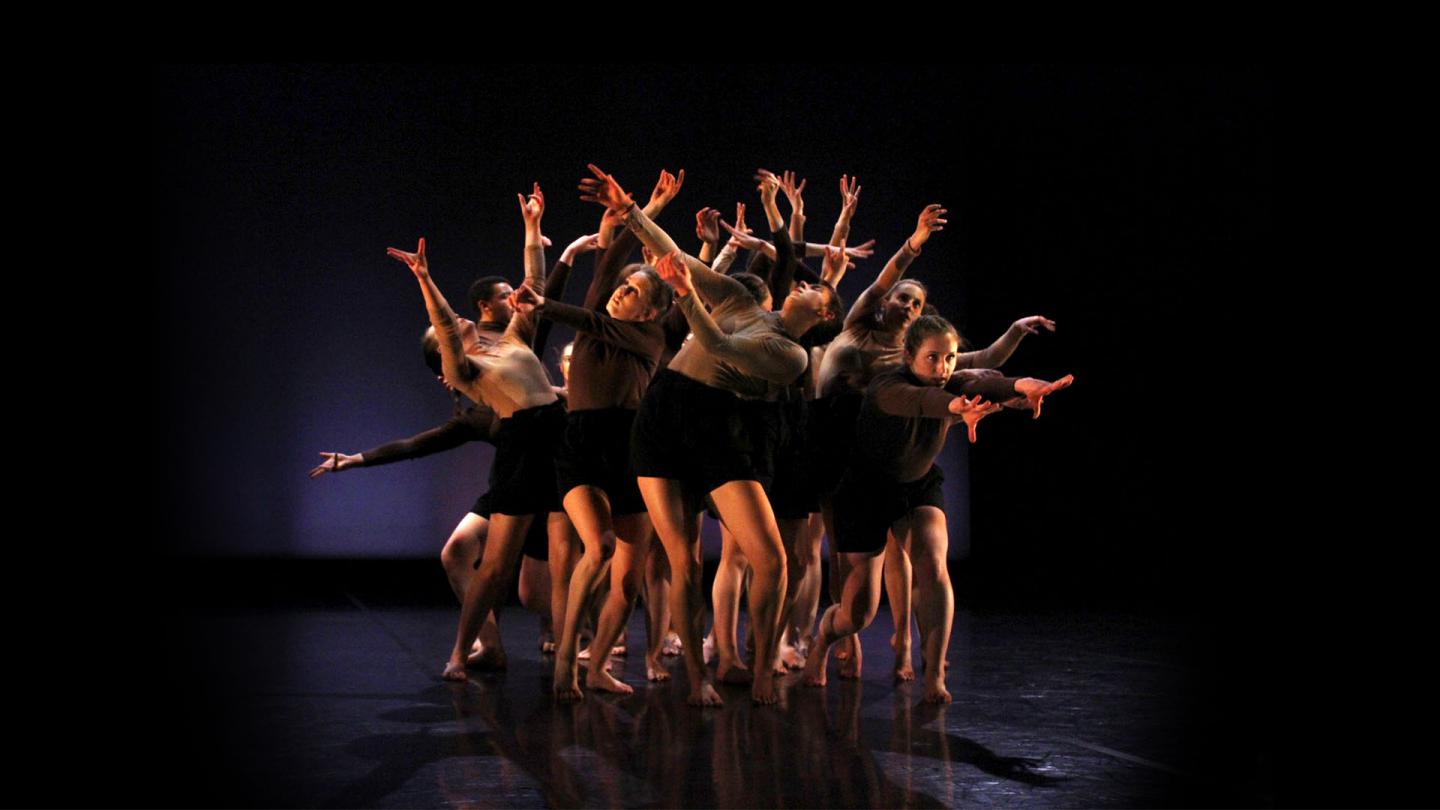 Group of student dancers close together each with their arms outstretched
