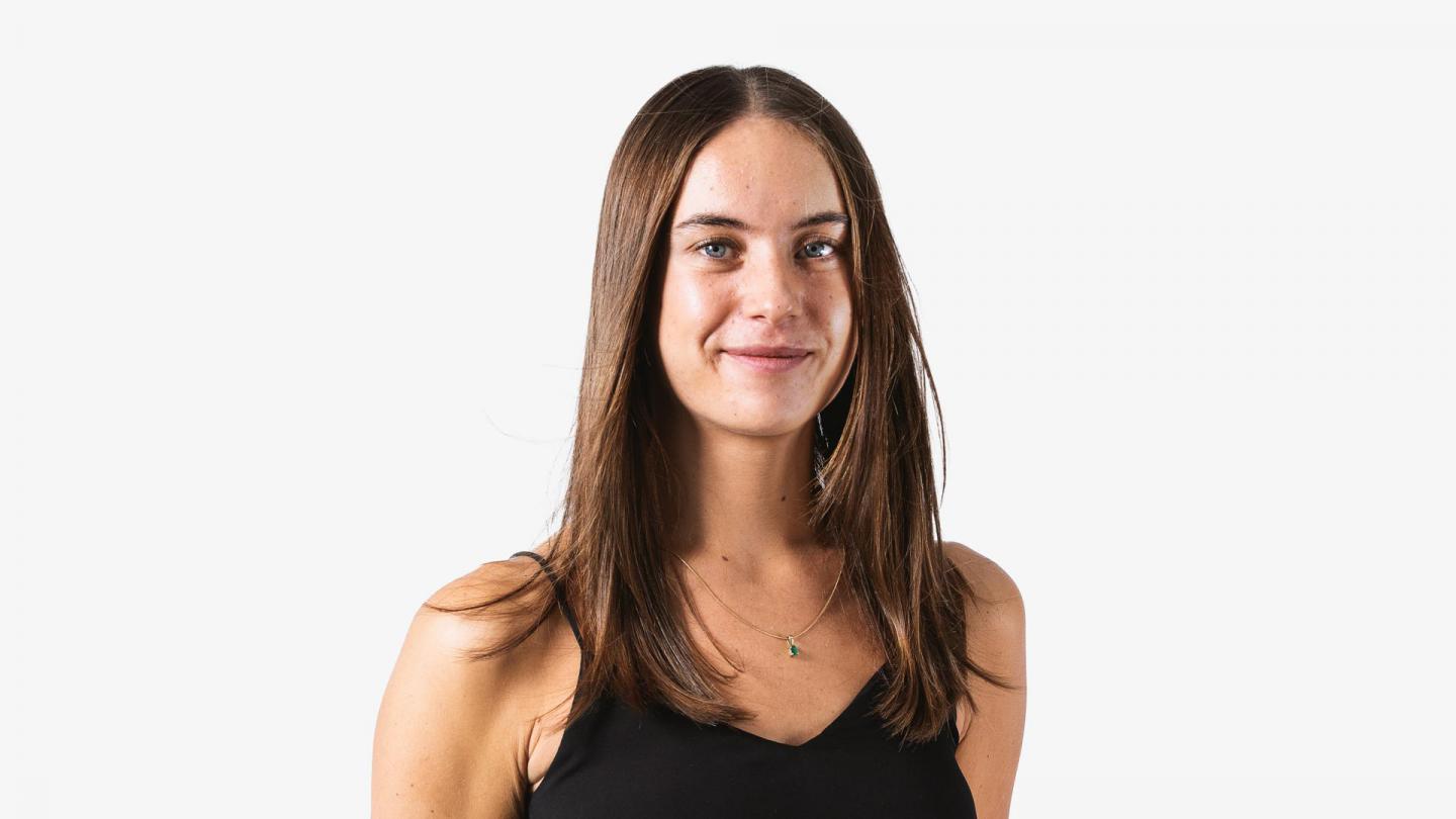 A headshot of a woman looking forward with dark brown hair and a black top