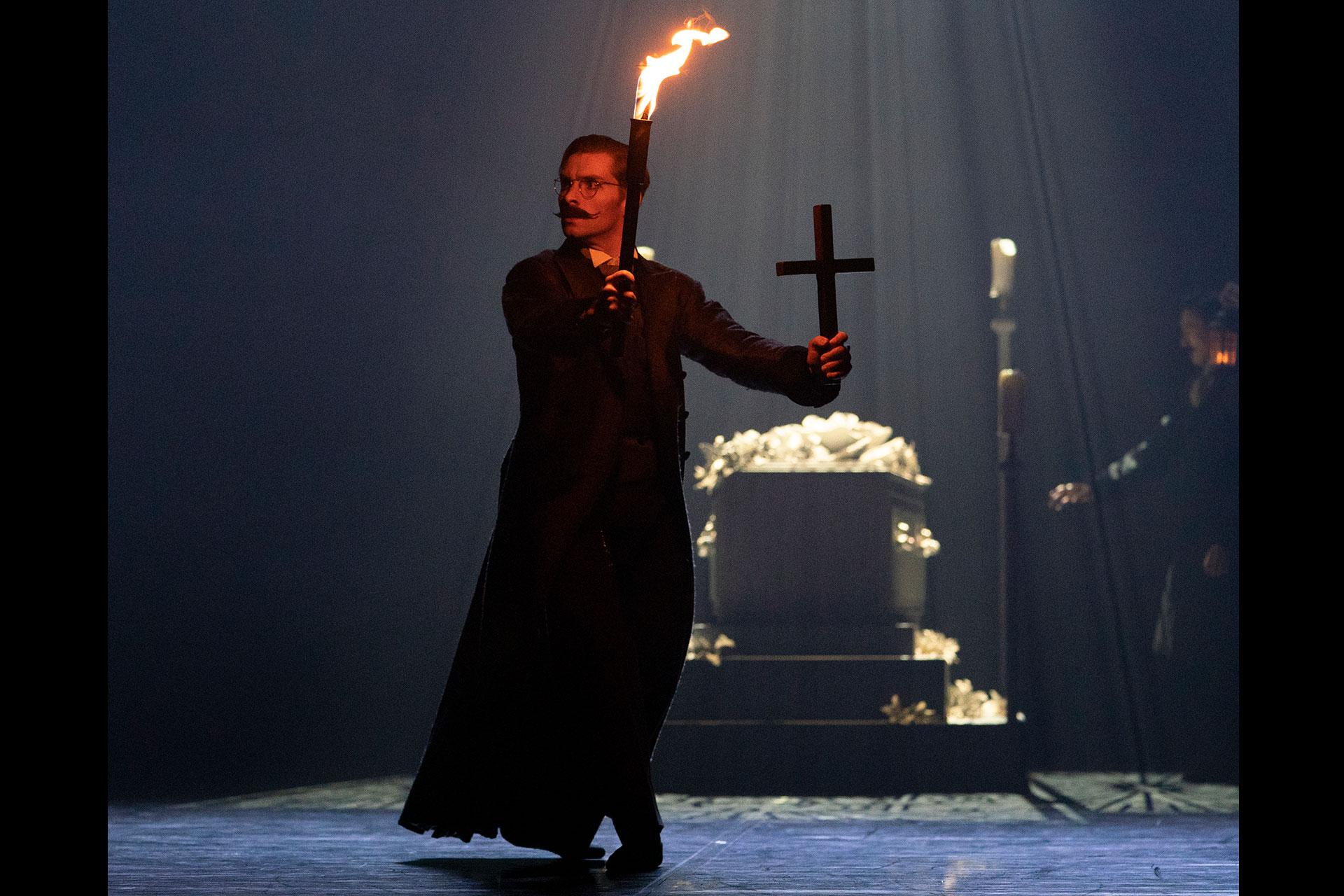 Van Helsing holds a torch in one hand and a crucifix in the other as he explores the tomb