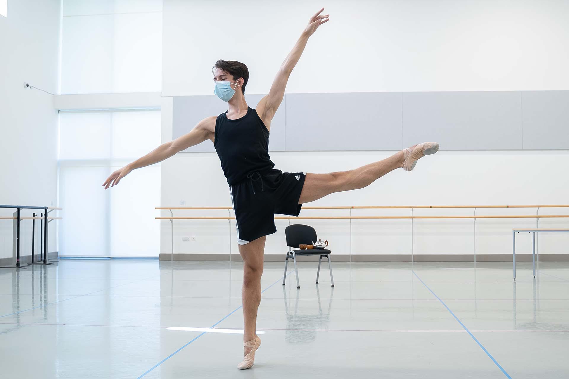 A dancer stands on one leg, the other outstretched beside him