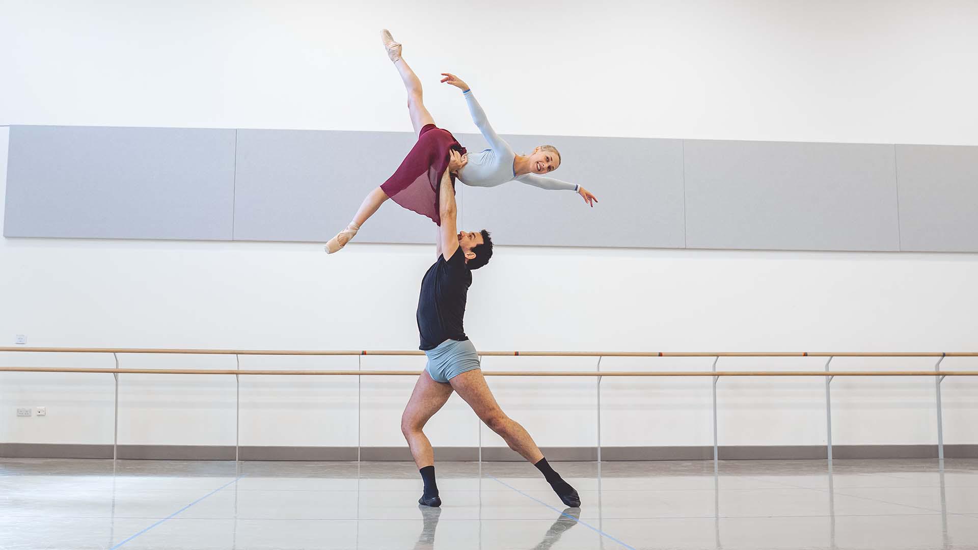 A male dancer lifting a female dancer high above his head