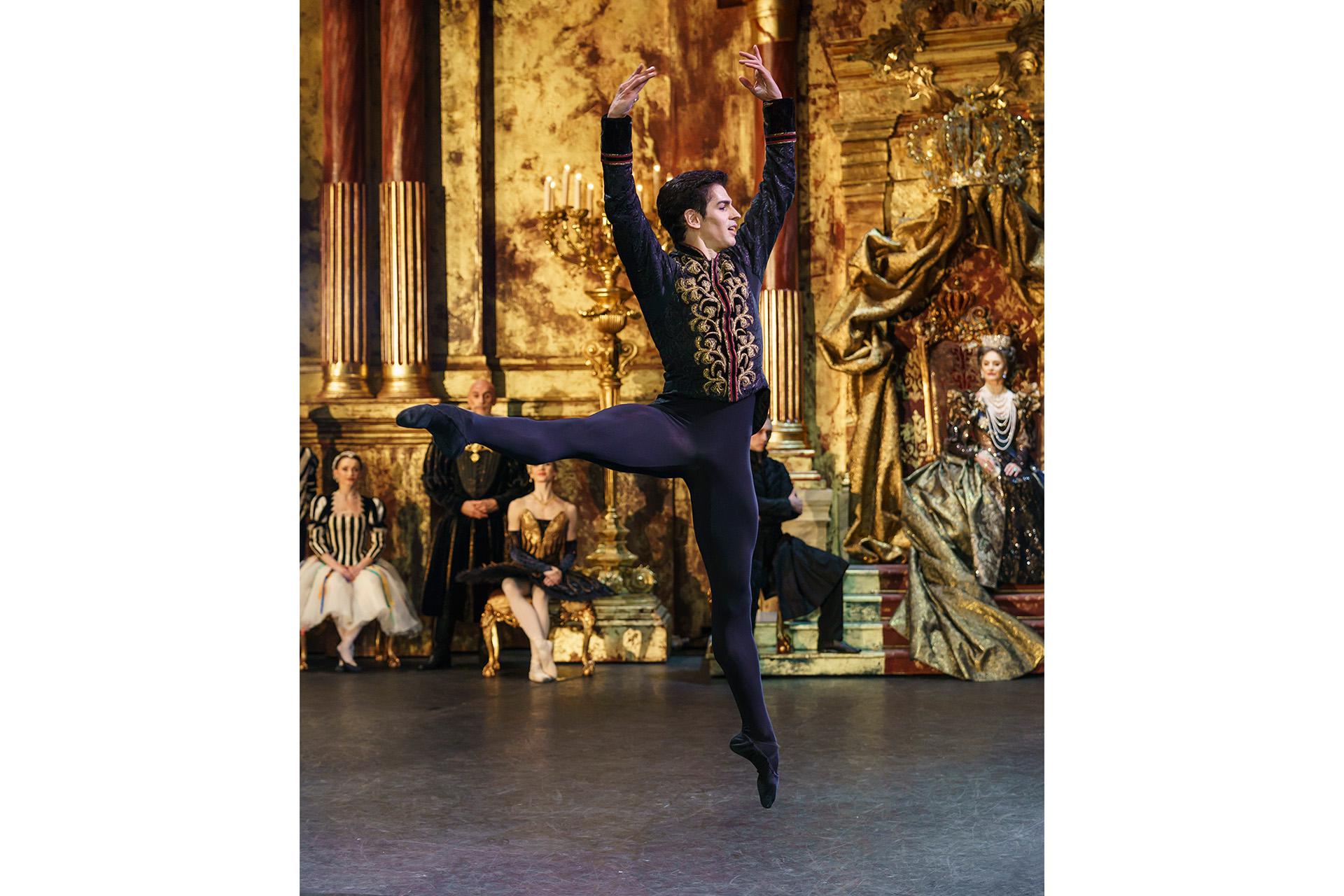 Dancer leaping with arms stretched above him and a leg parallel to the ground