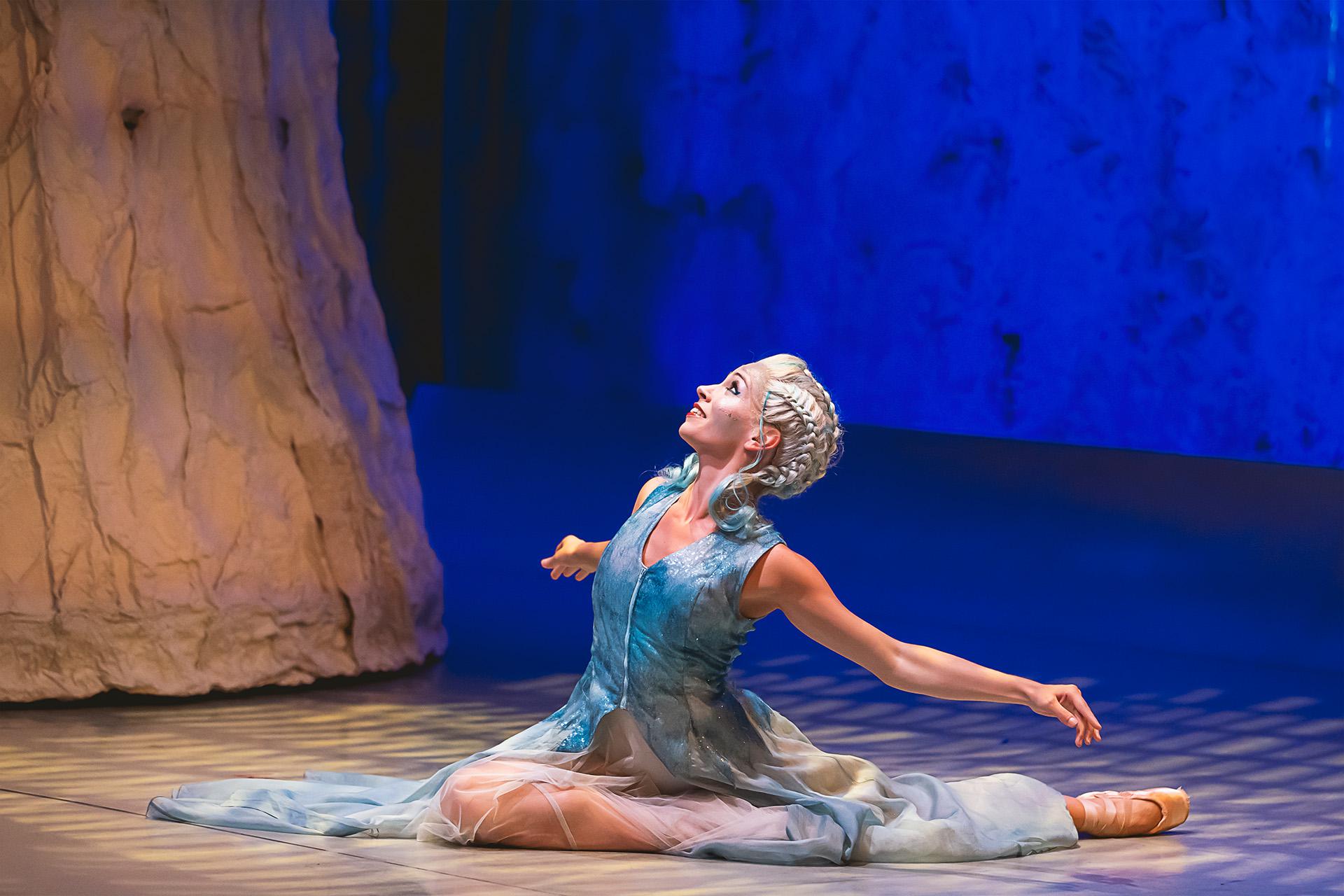 Marilla in a blue dress, sat on the floor looking at the stars, smiling wanly