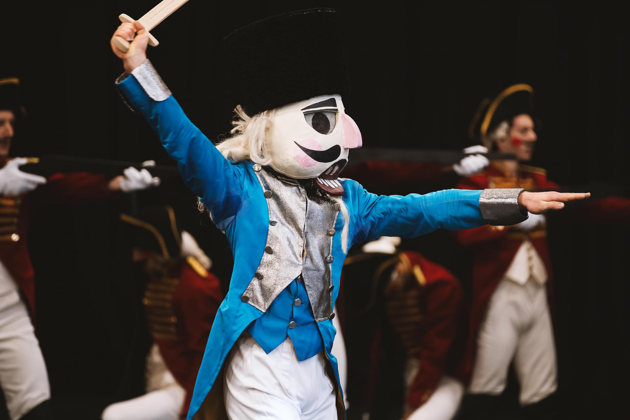 Dancer dressed as a giant Nutcracker has a sword raised