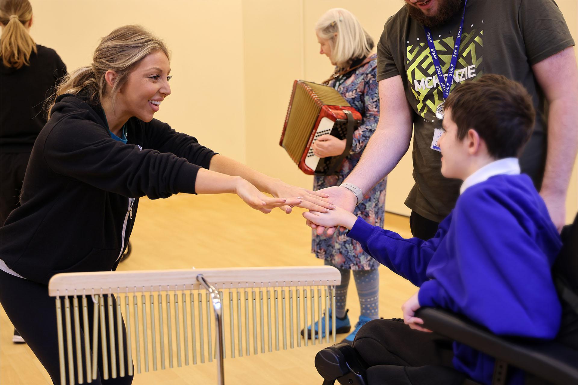 A wheelchair user joining in as an instructor shows a dance move with her arms.