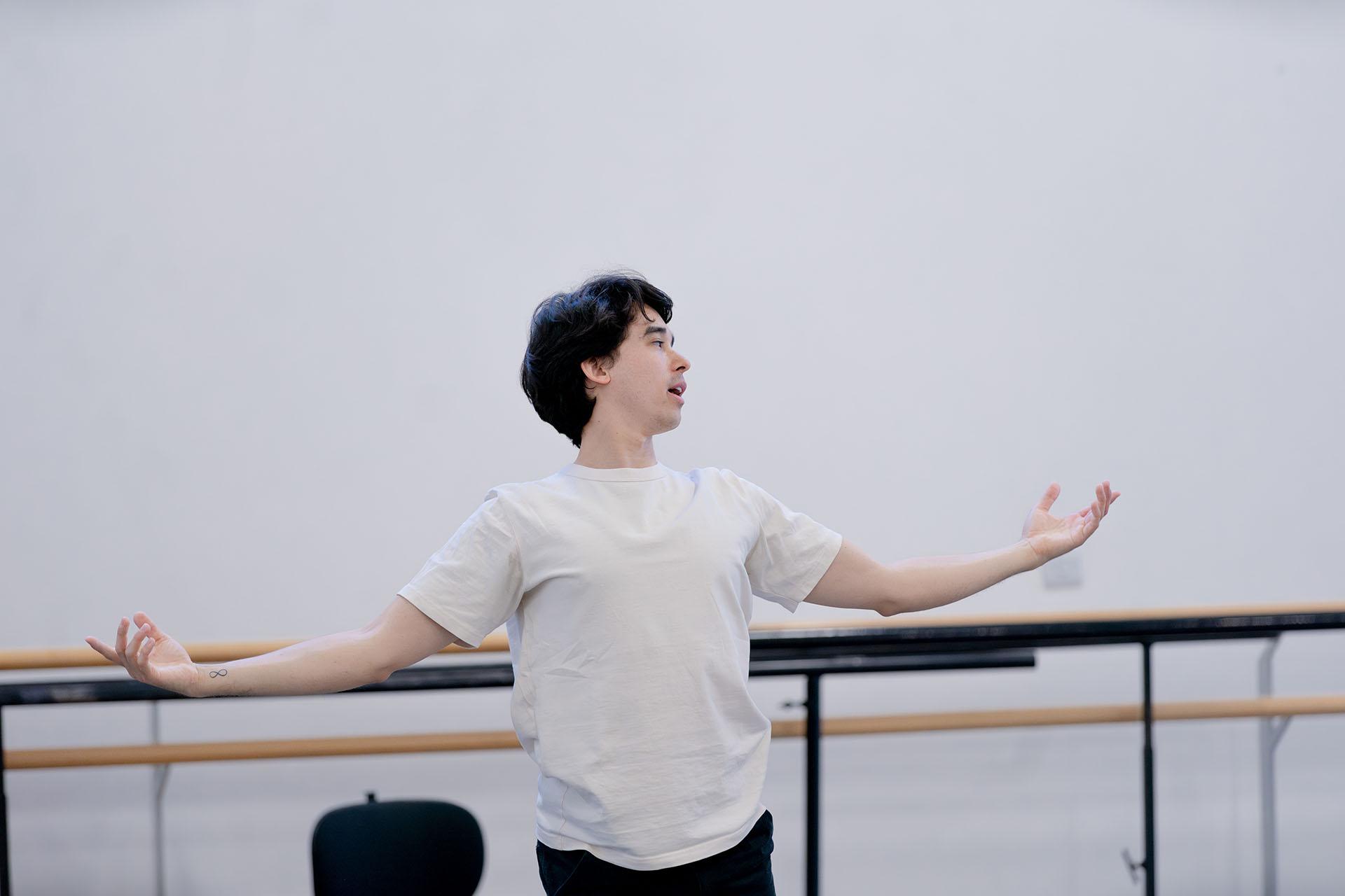 Choreographer leaning slightly to his back, arms spread with palms facing upwards