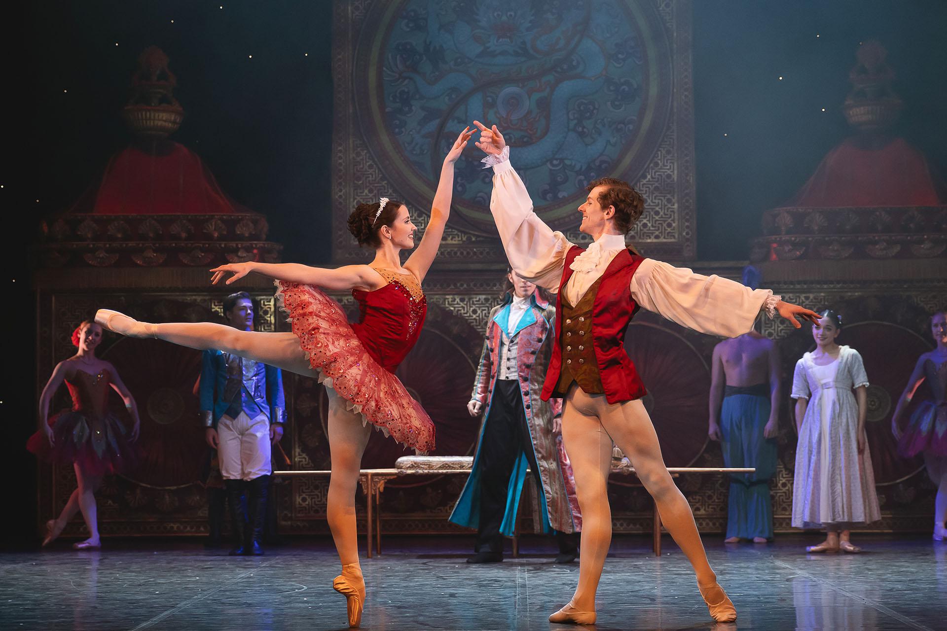 The Sugar Plum Fairy posing arabesque as the Cavalier offers a steadying hand