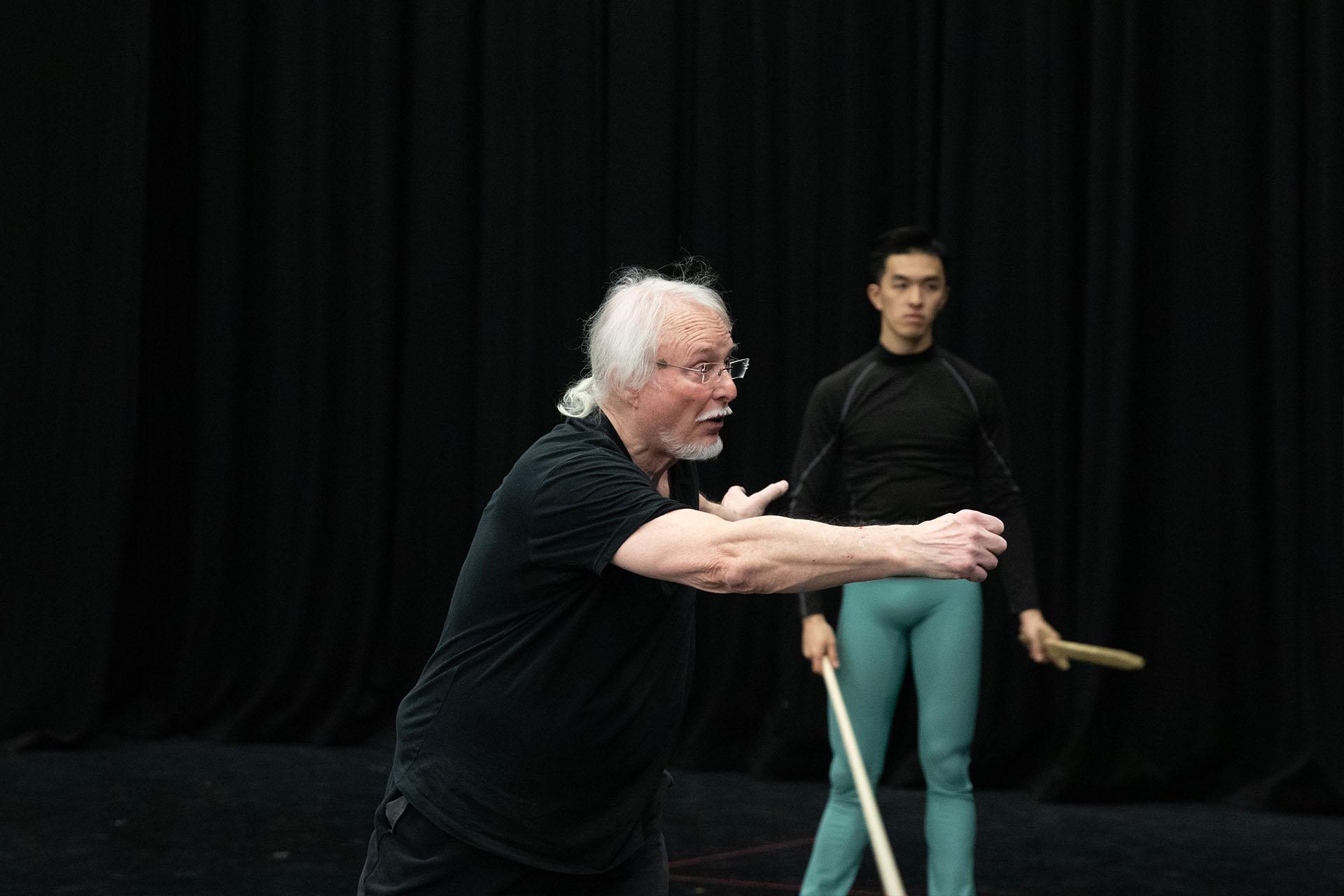 The fight director of Romeo & Juliet in black T-shirt and trousers speaks to people off-camera