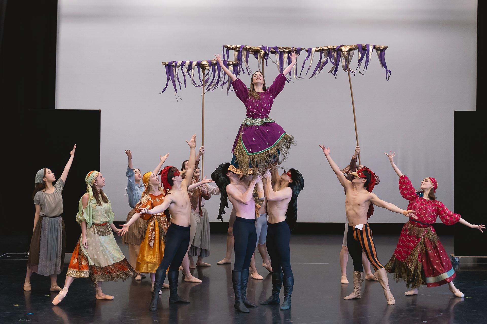 Group photo of townspeople lifting one of their number tall while others present and celebrate them