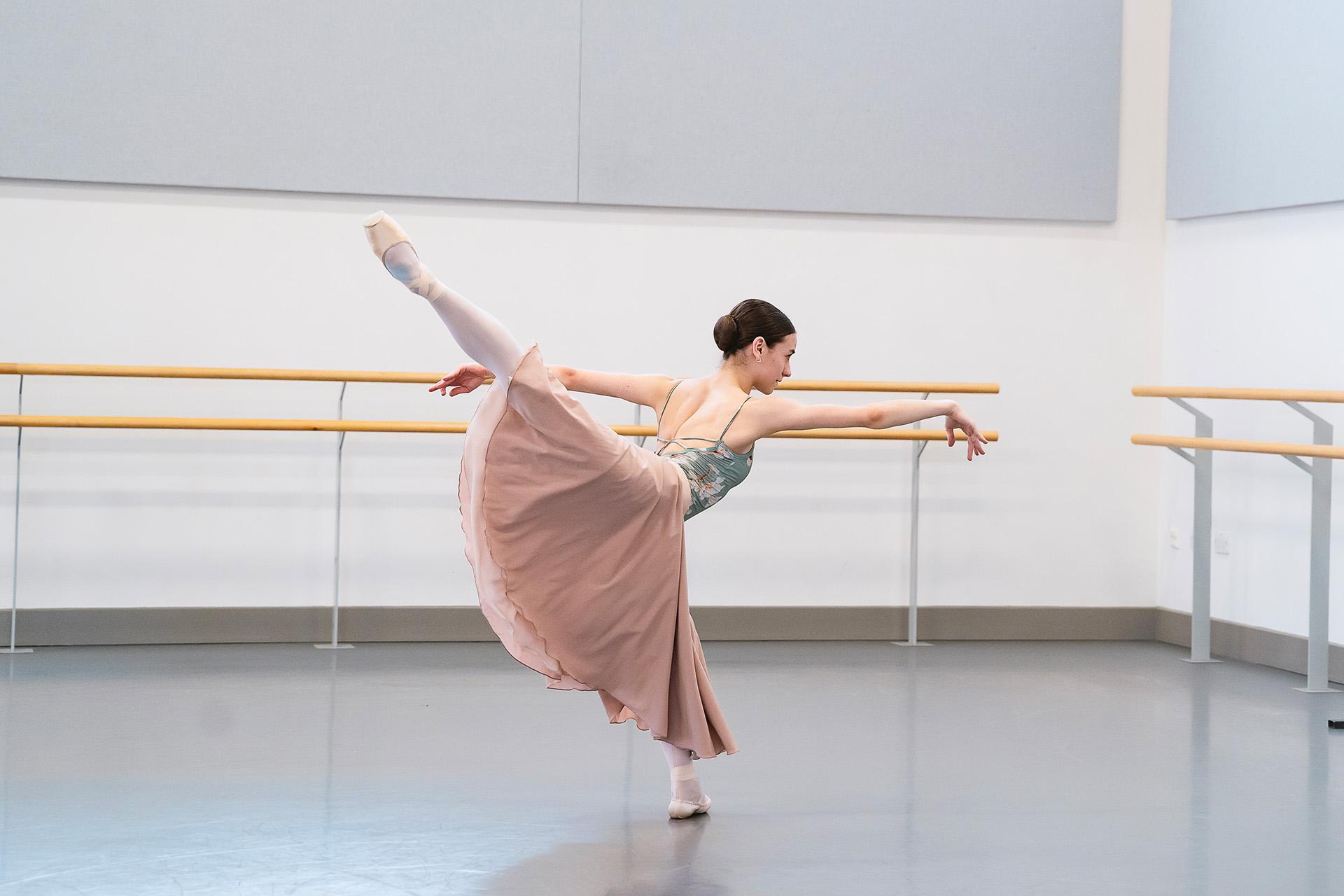 Dancer in long skirt stands arabesque developpe