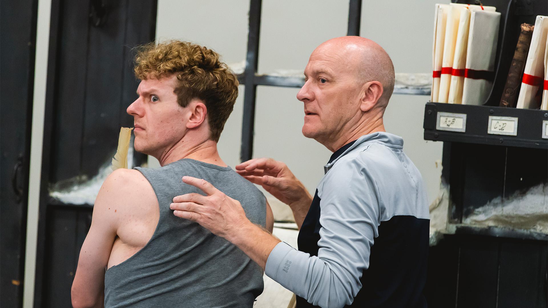 A dancer and rehearsal director looking over their shoulders