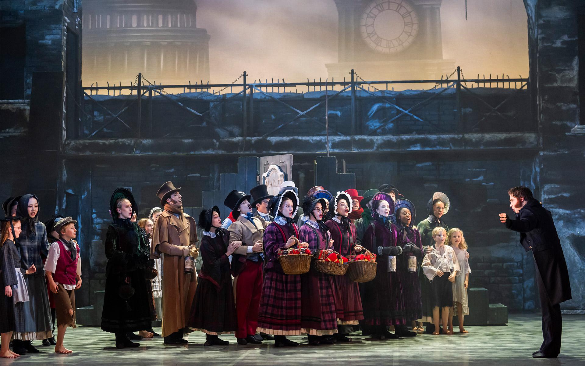 A photo of a group of dancers singing in Victorian era clothing