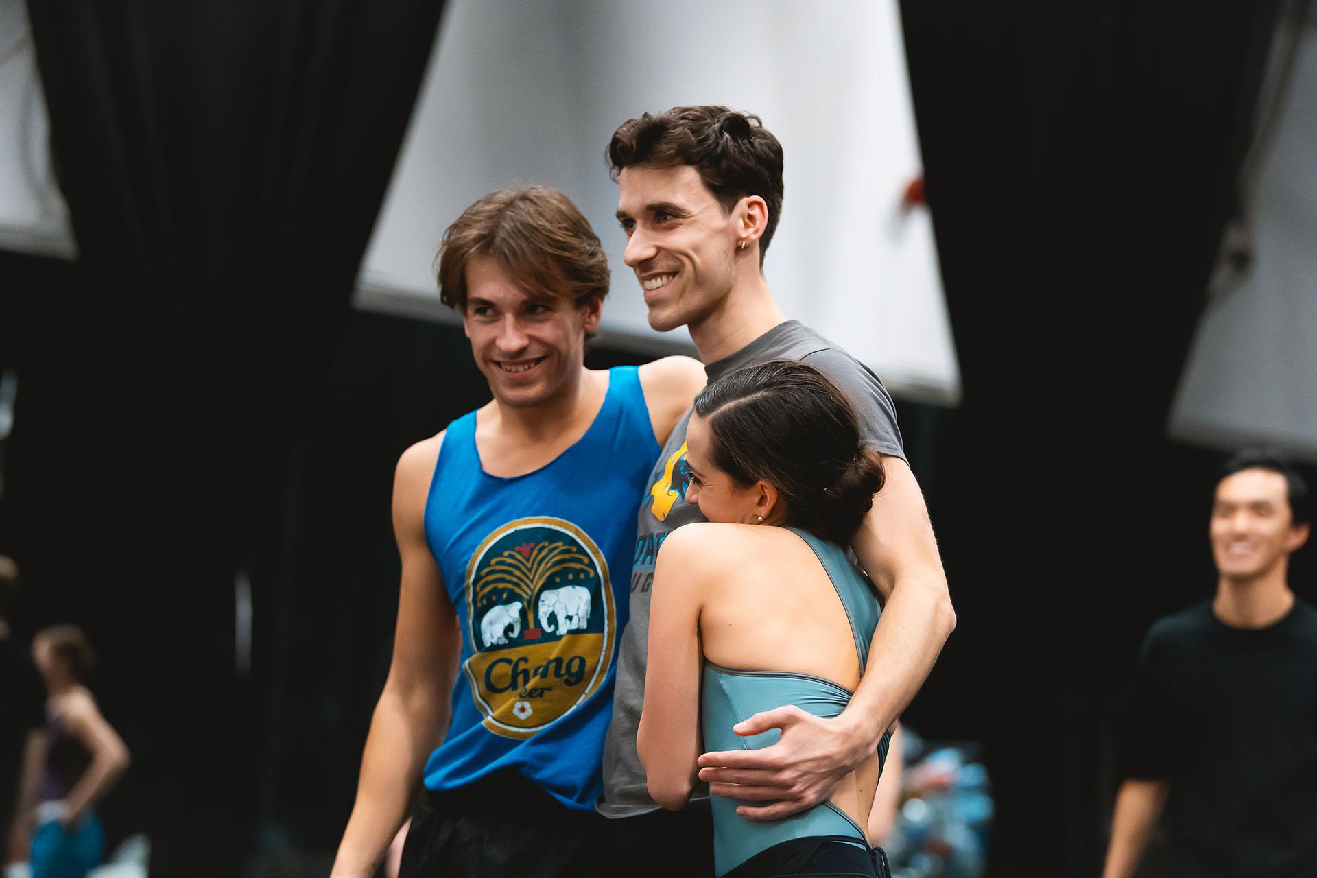 Three people in the rehearsal room smiling and hugging each other