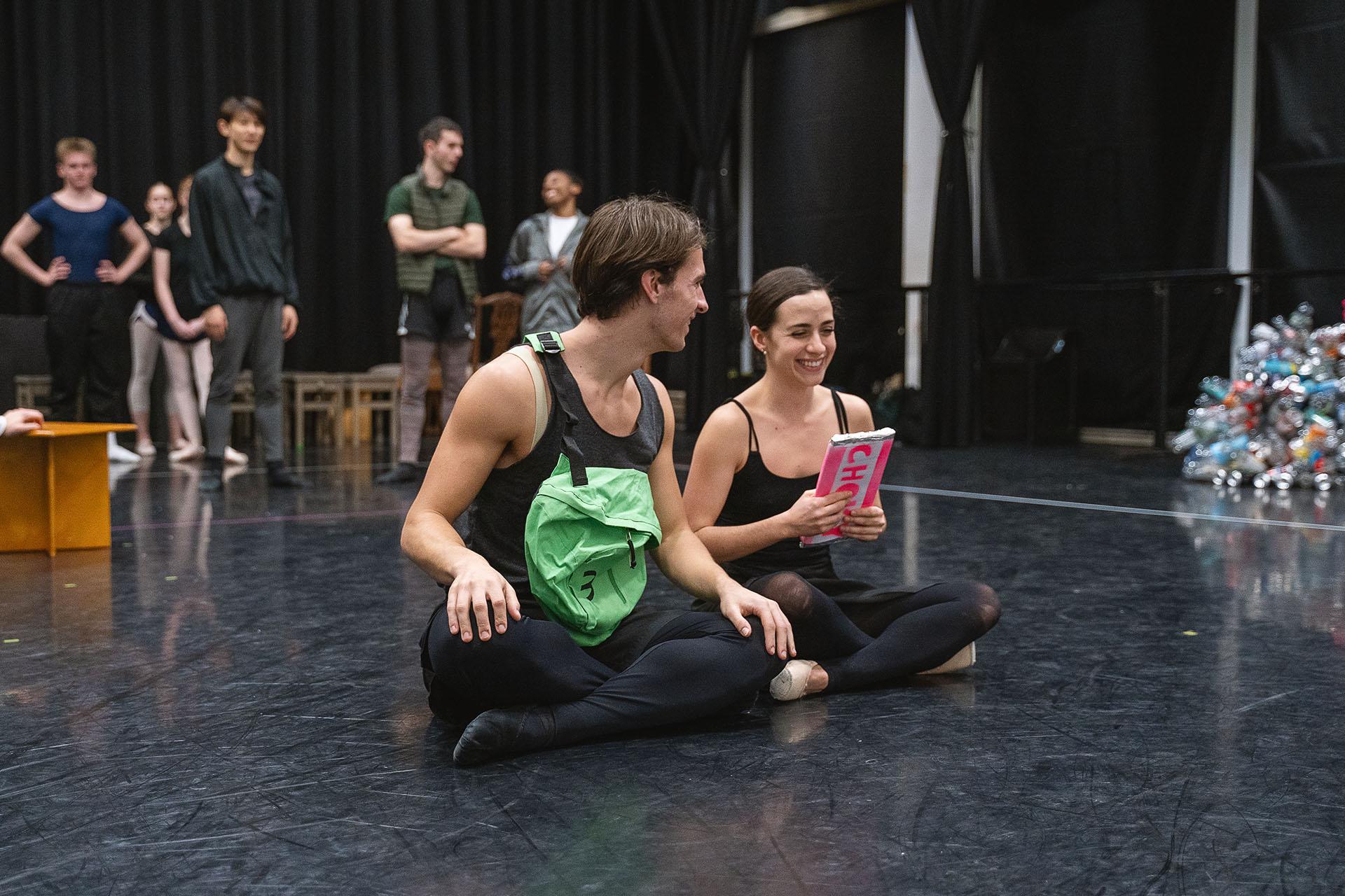 Two dancers sat cross legged, smiling