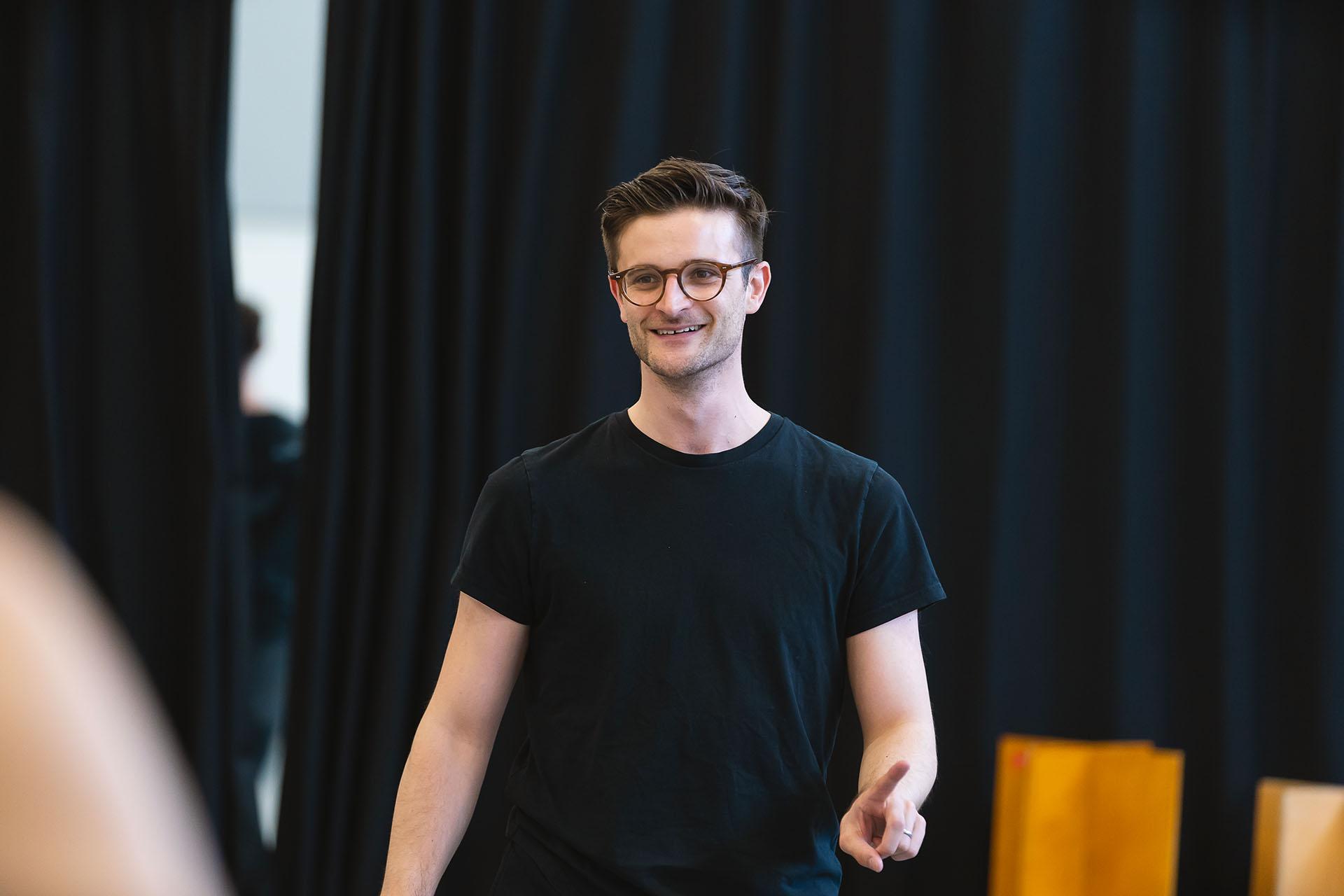 Nicola Gervasi dressed in a black T-shirt and in glasses smiles warmly as he raises a finger in correction.