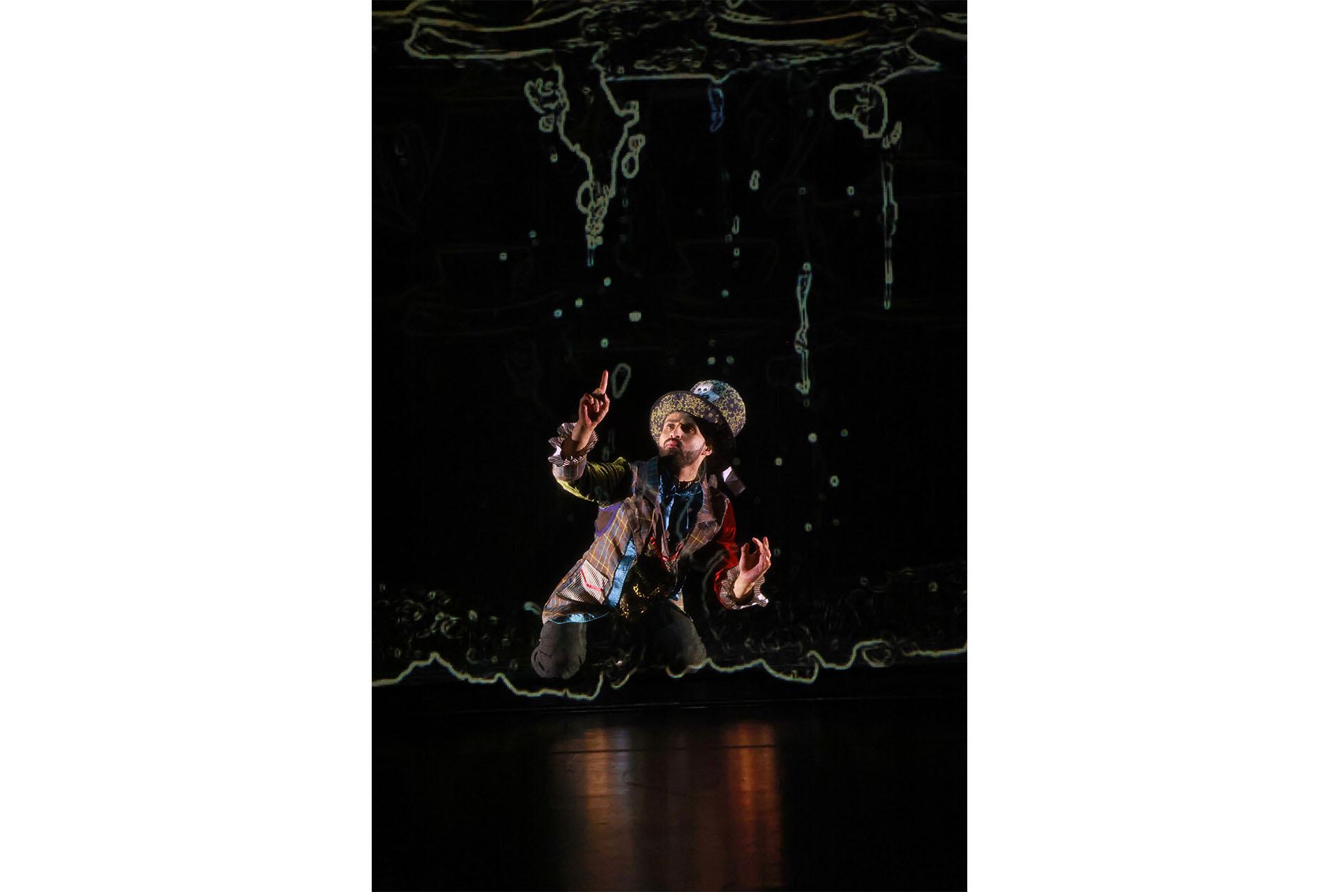 A man in a large top hat kneels on the floor and draws magically in the air