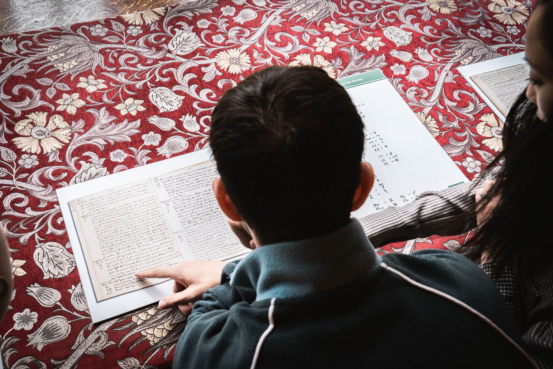 Laid upon an ornate fabric, Northern Ballet dancer Albert González Orts examines one of Anne Lister's diaries.