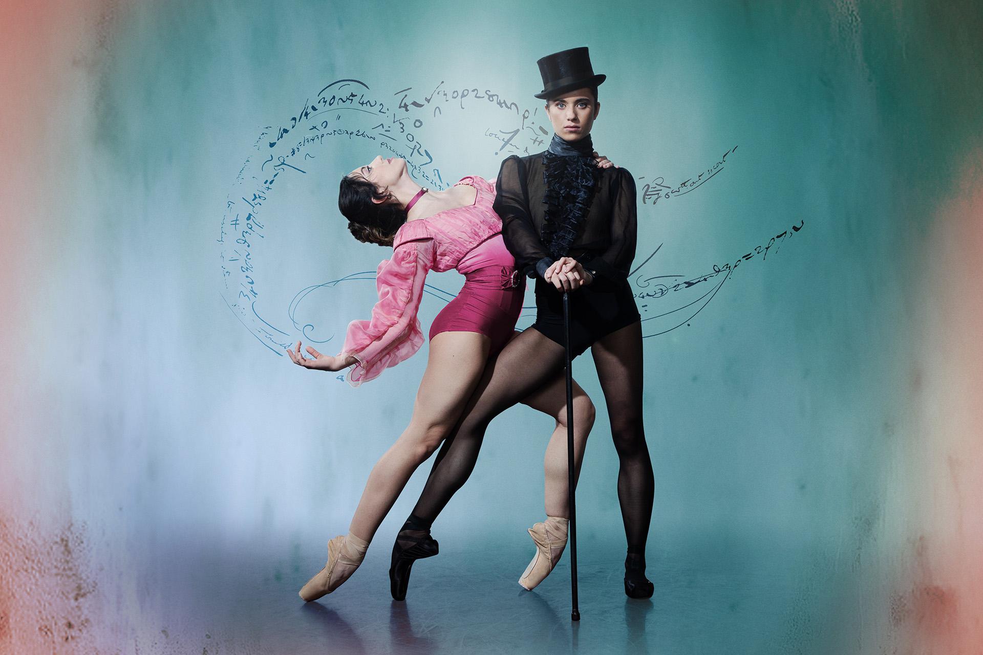 Wearing a black top hat and pointe shoes, the character of Gentleman Jack looks directly at the camera hands on a cane, a woman in pink hold onto her and leans back suggestively