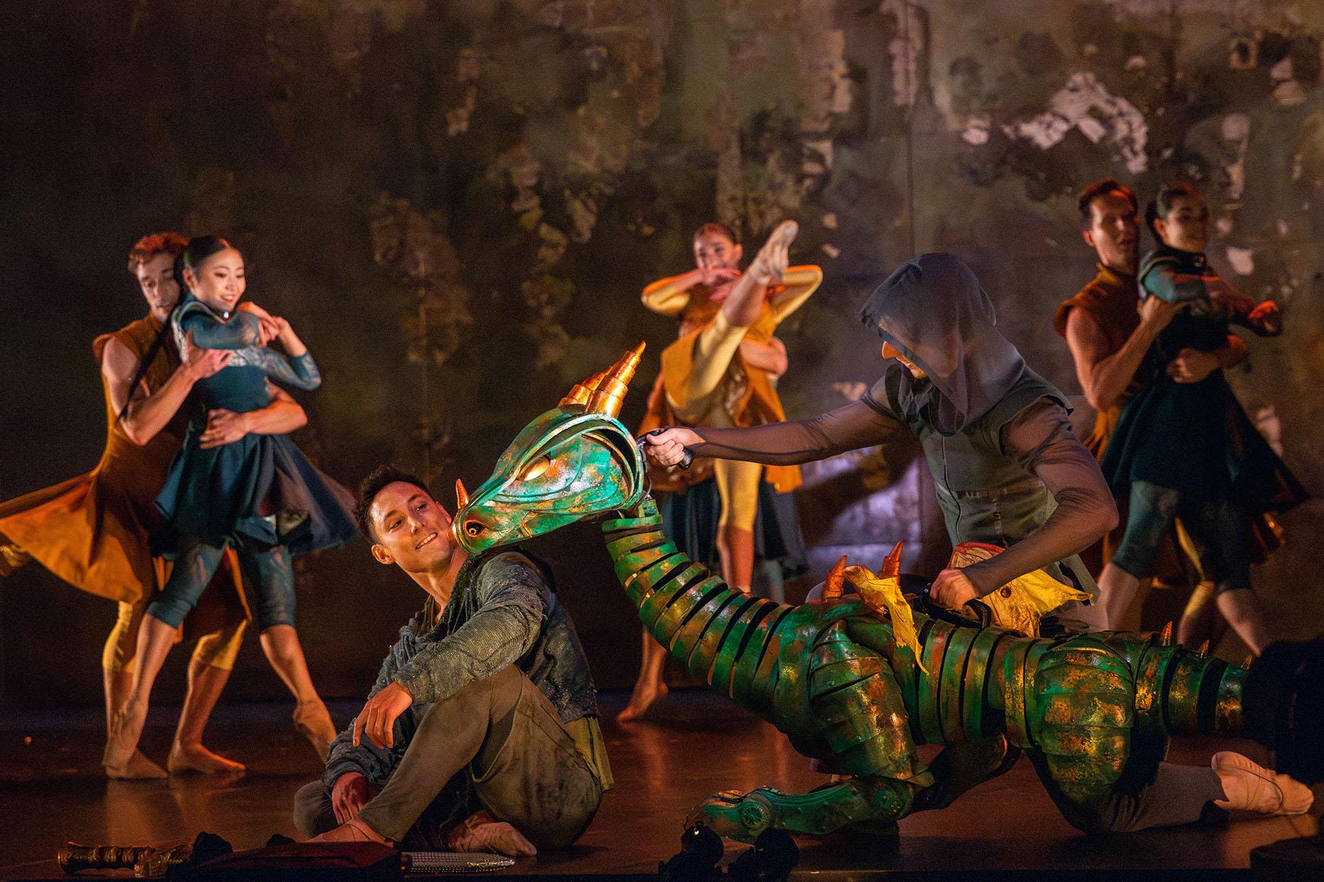 The baby dragon nuzzles Merlin playfully as he smiles