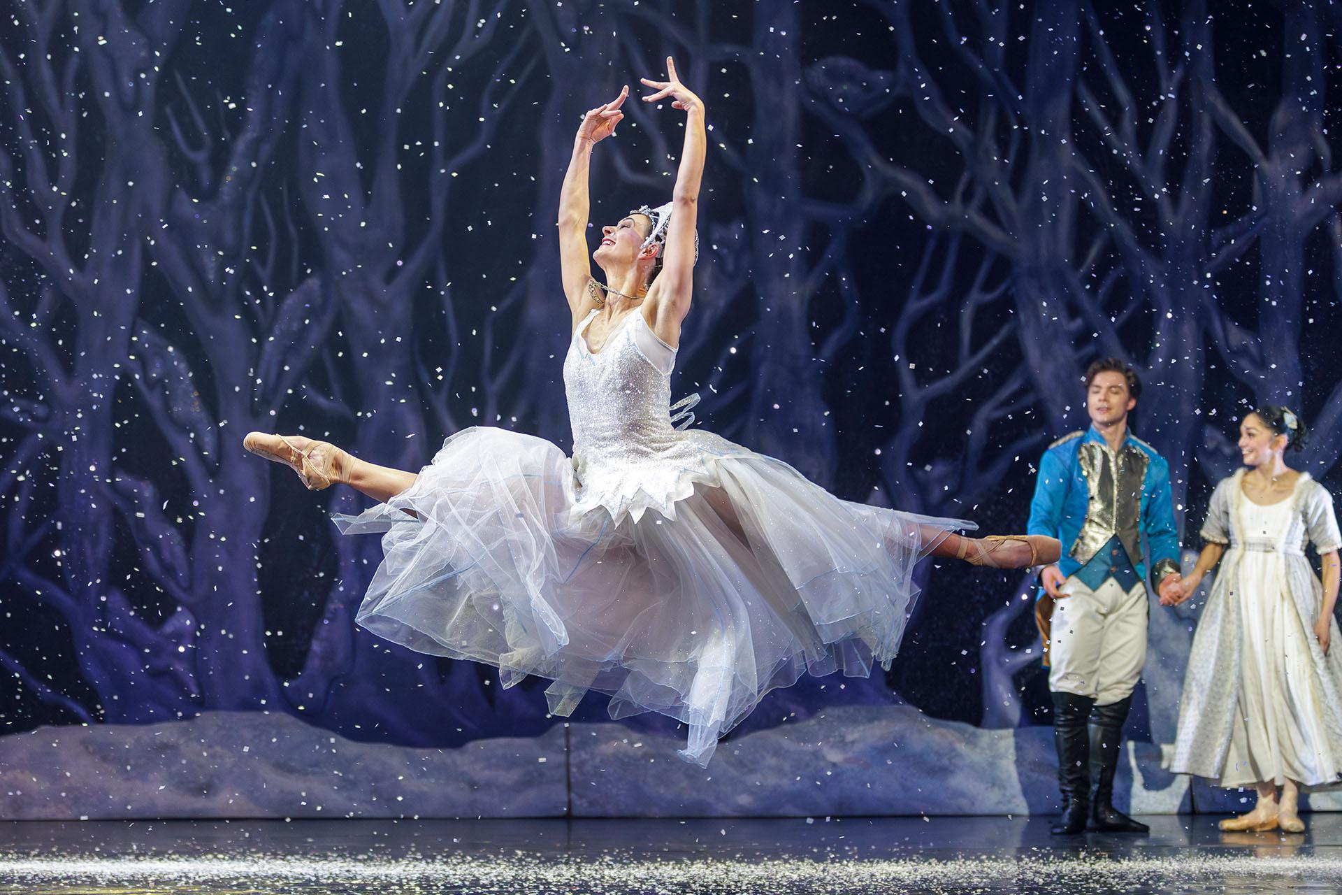 A dancer in white as snow dress and sparkline tiara leaps across the snow