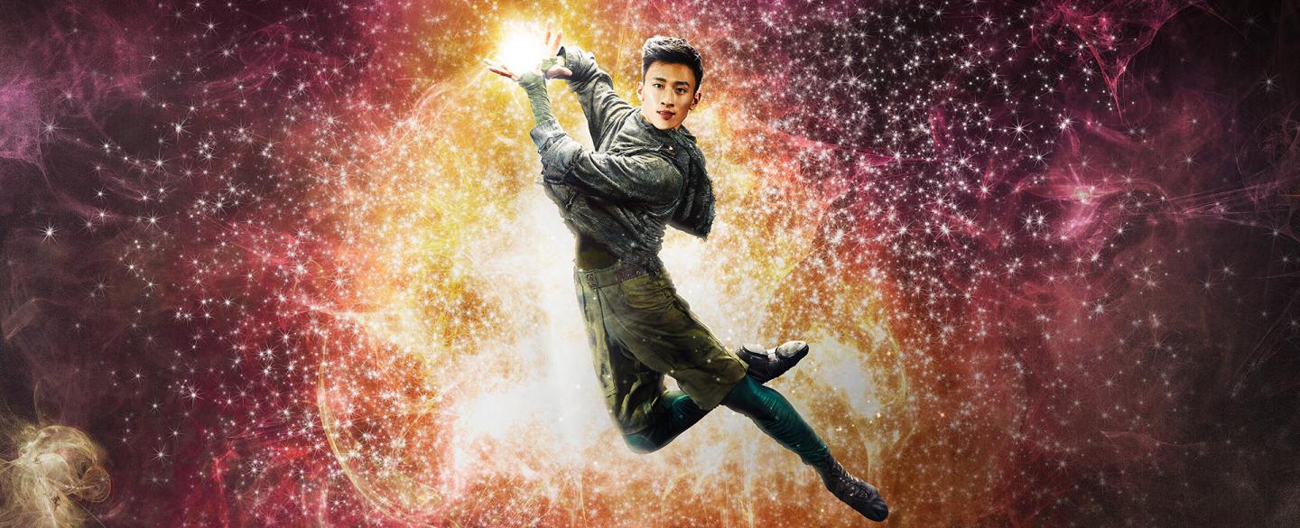 Dancer leaps holding light in his hands.