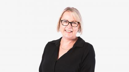 Woman in glass, medium short, straight blonde hair, black shirt against a white background