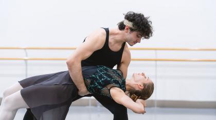 A dancer leans back horizontal help by another supporting her while looking into her eyes