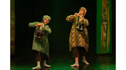 Two birdwatchers walking through a forest each dressed in a camouflage anorak