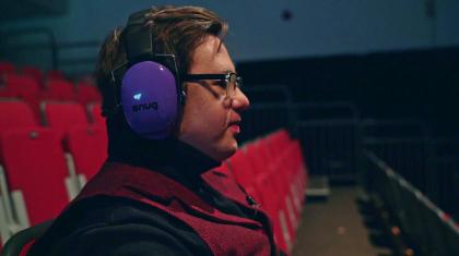 Man sat on the seats in the auditorium wearing ear defenders