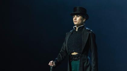 Standing proud, cane in one hand, hearing a tall hat and long coat, Anne Lister looks imperious